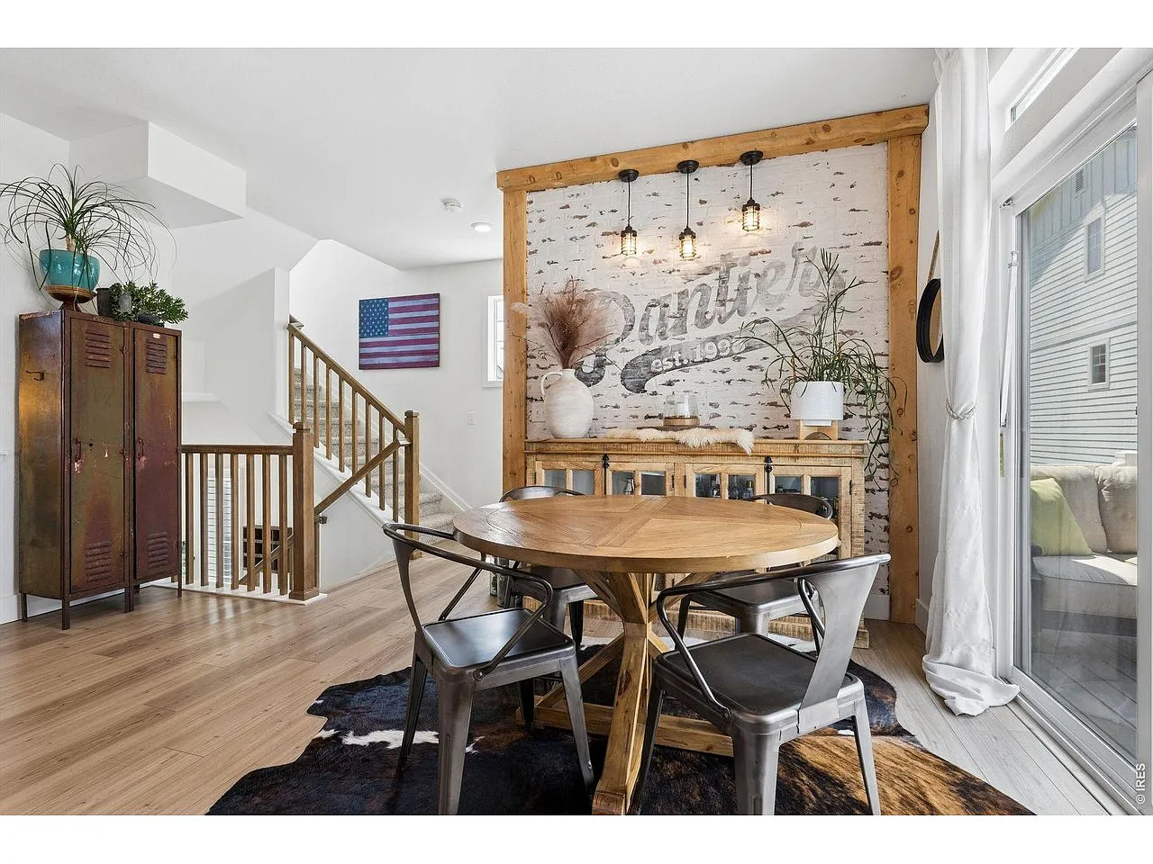 Dining area with whitewashed brick accent wall and Edison pendant lights