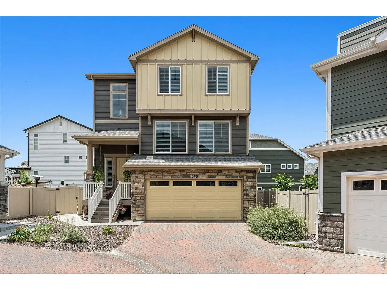 Front exterior with stone-accented two-car garage and covered porch on a cul-de-sac