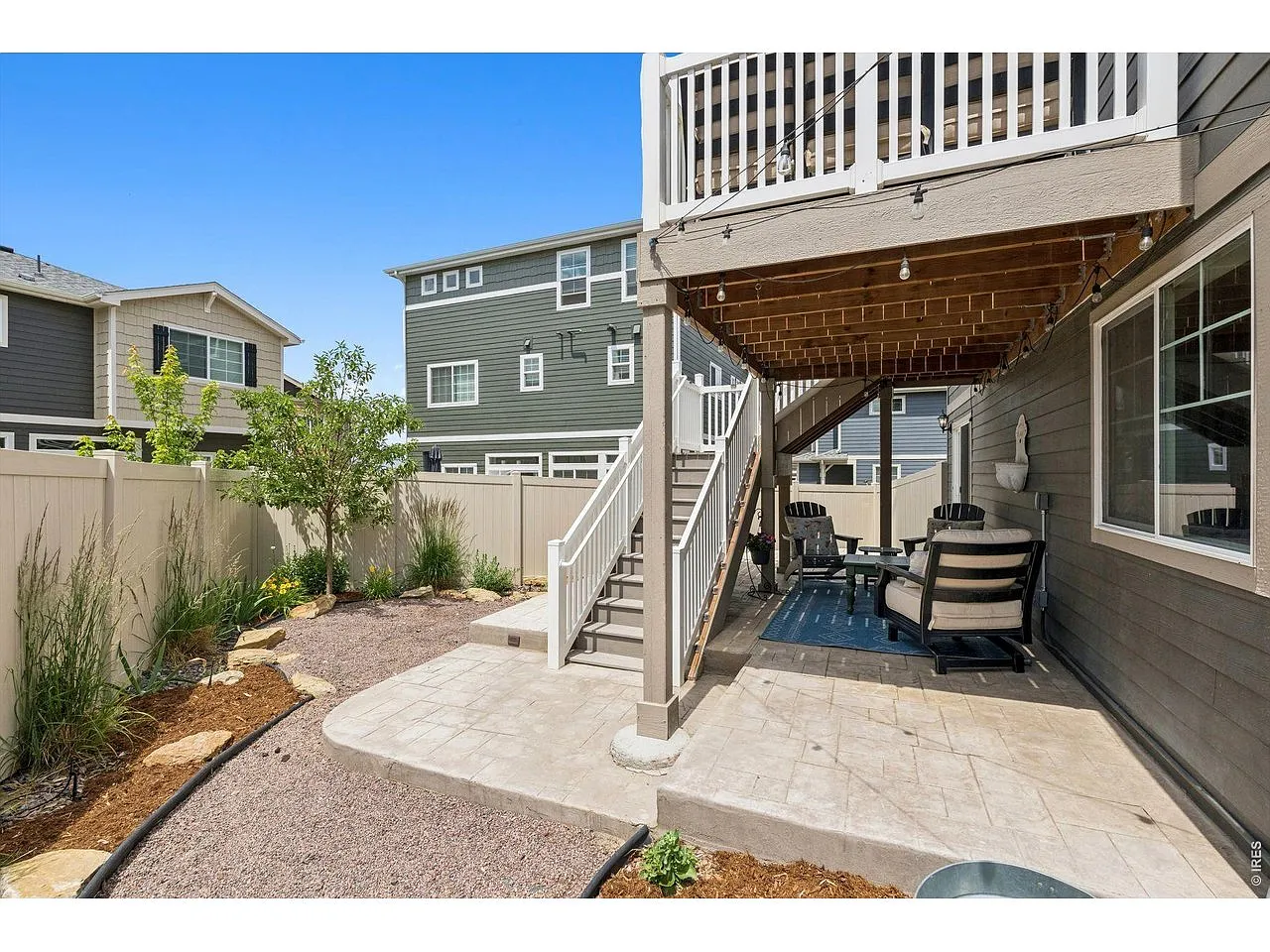 Walkout patio under the deck with string lights and seating