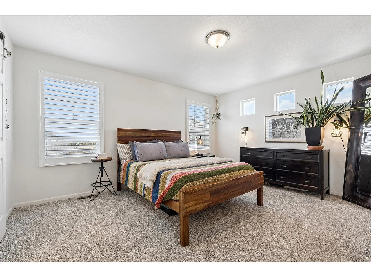 Primary bedroom with king bed, plantation shutters and high windows
