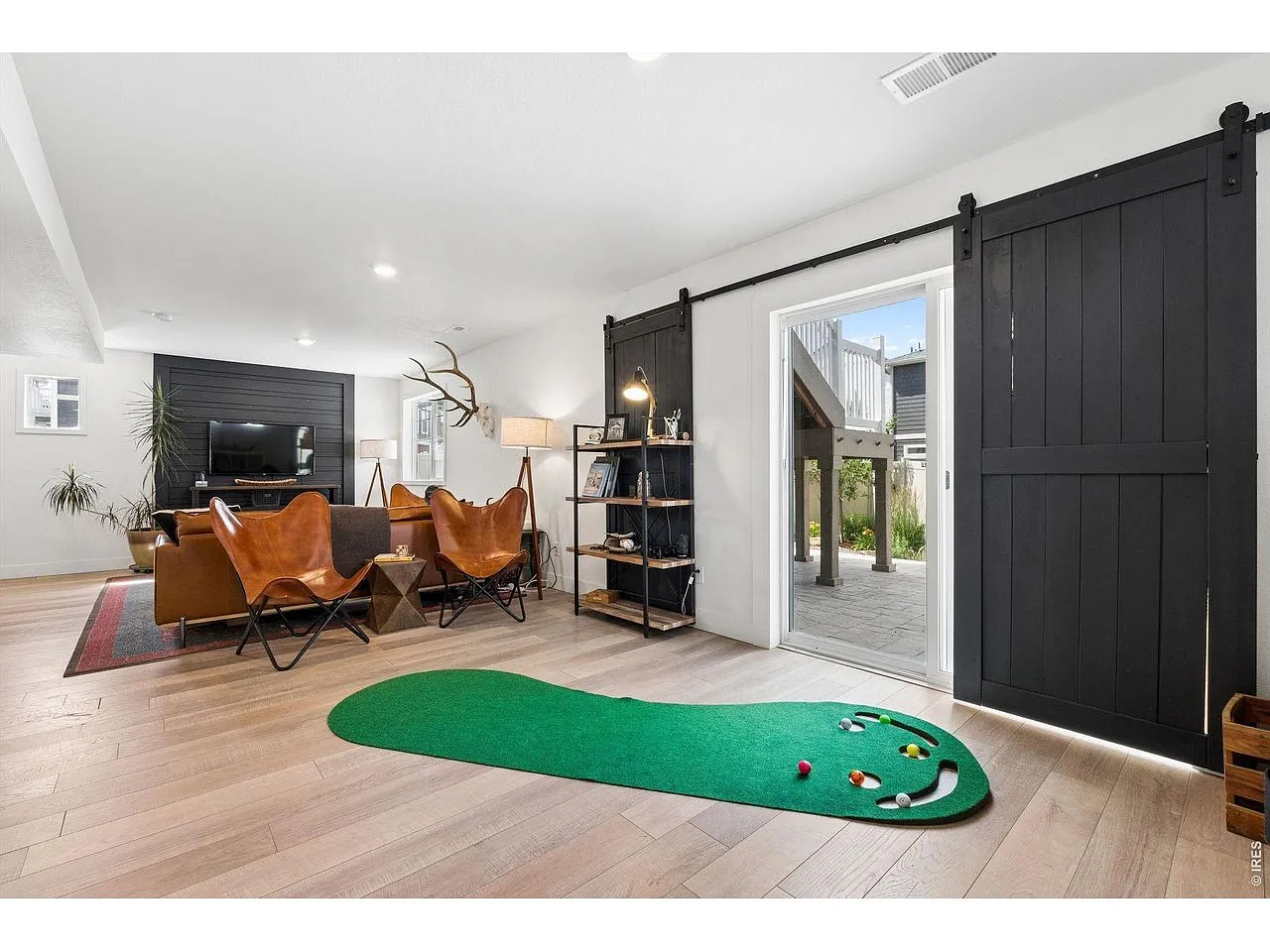 Walkout rec room with putting green, lounge chairs, barn doors and patio access